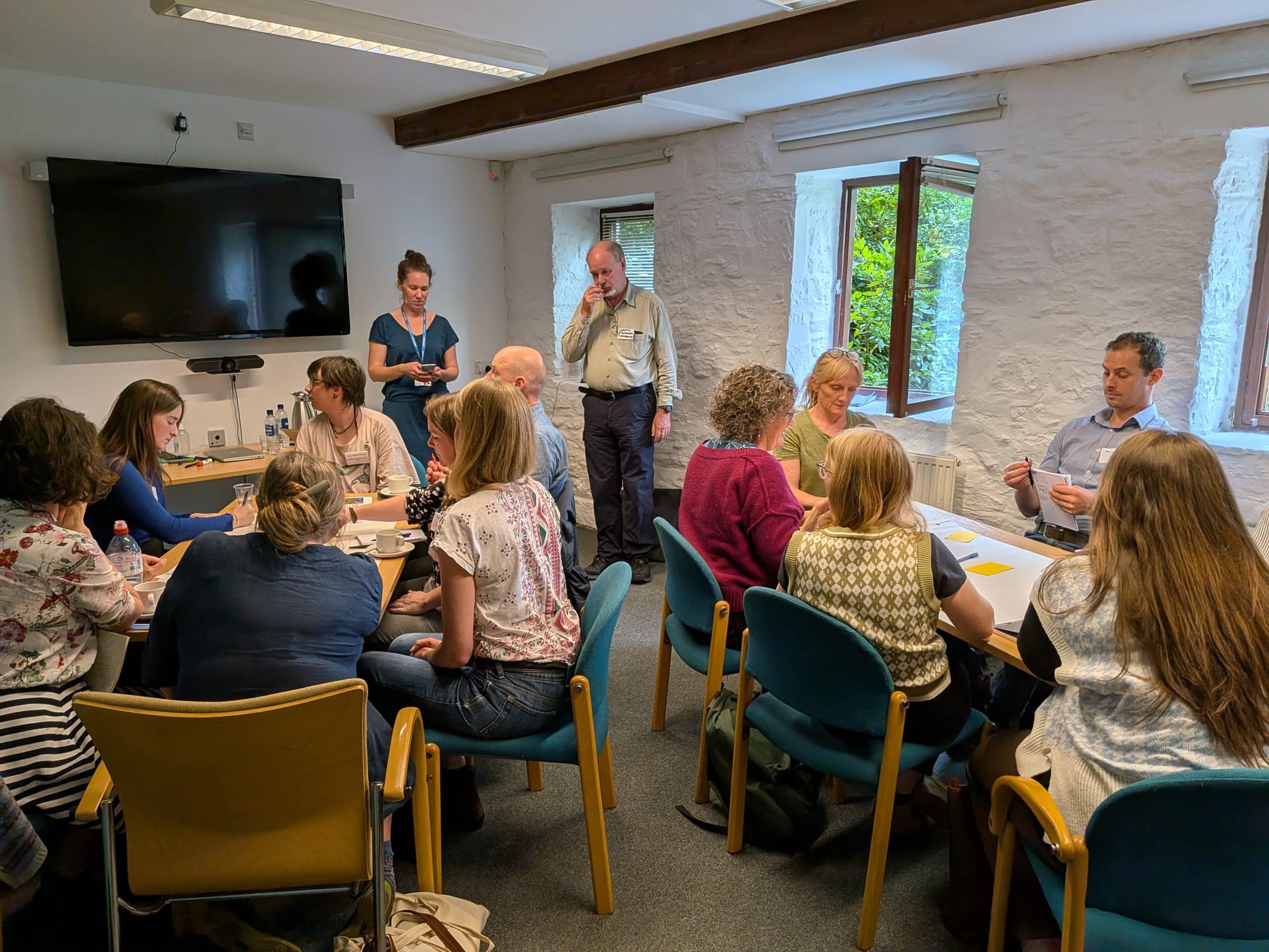 two people presenting in front of people sat around tables
