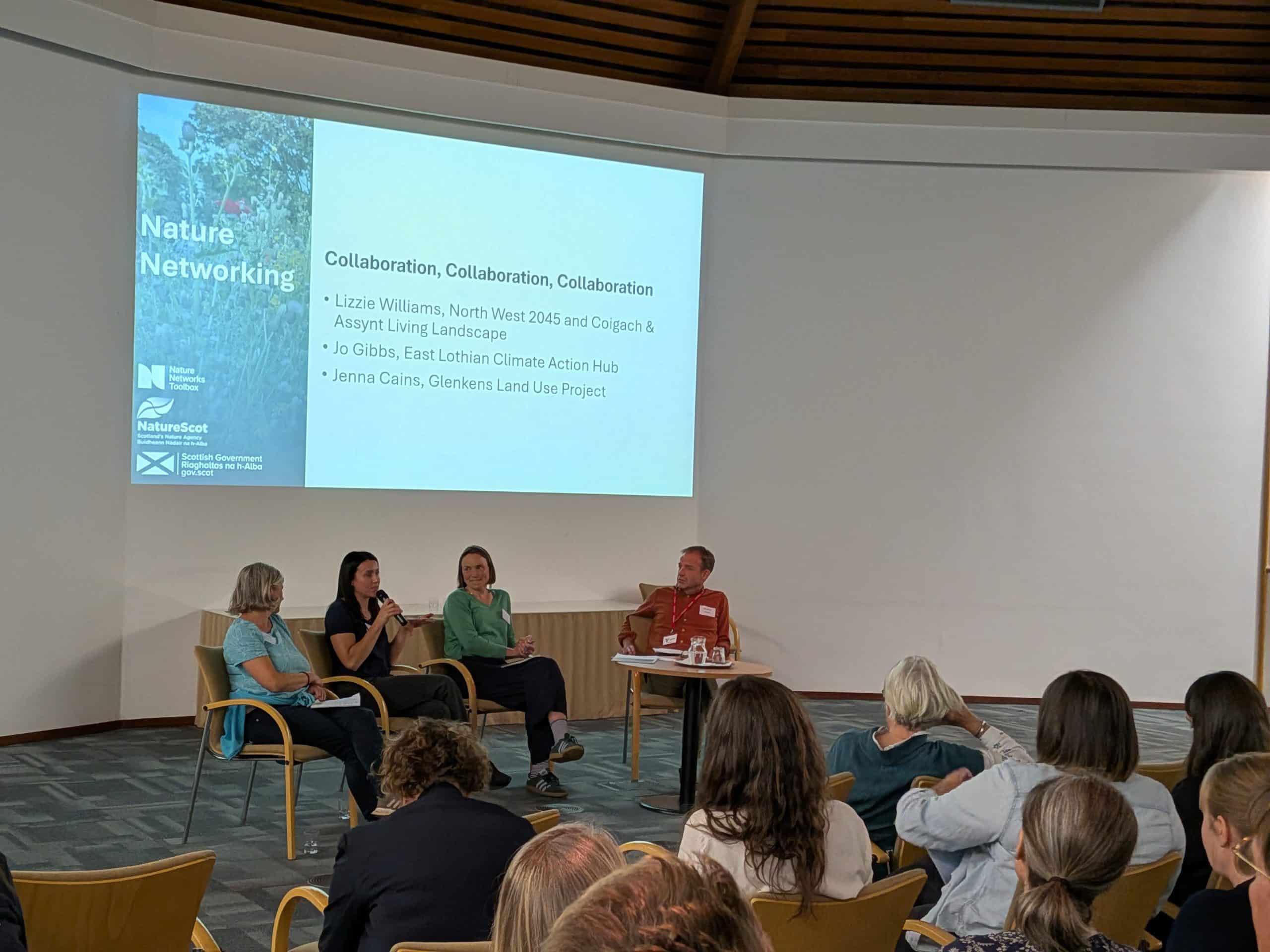 Panel of 4 people speaking in front of a screen with the panel title 'collaboration, collaboration, collaboration'
